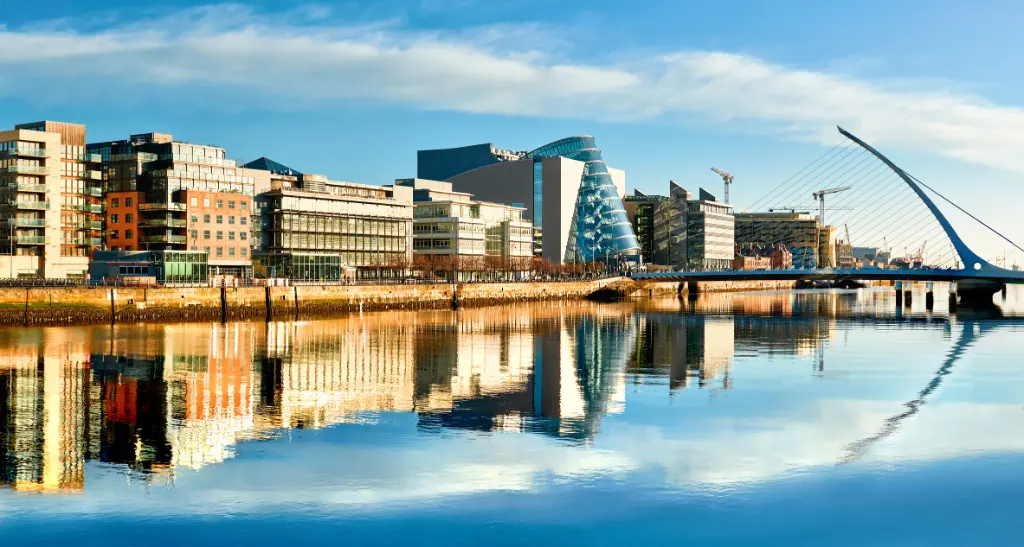 Moderne Gebäude und Büros am Fluss Liffey in Dublin an einem sonnigen Tag, mit der Harp-Brücke auf der rechten Seite