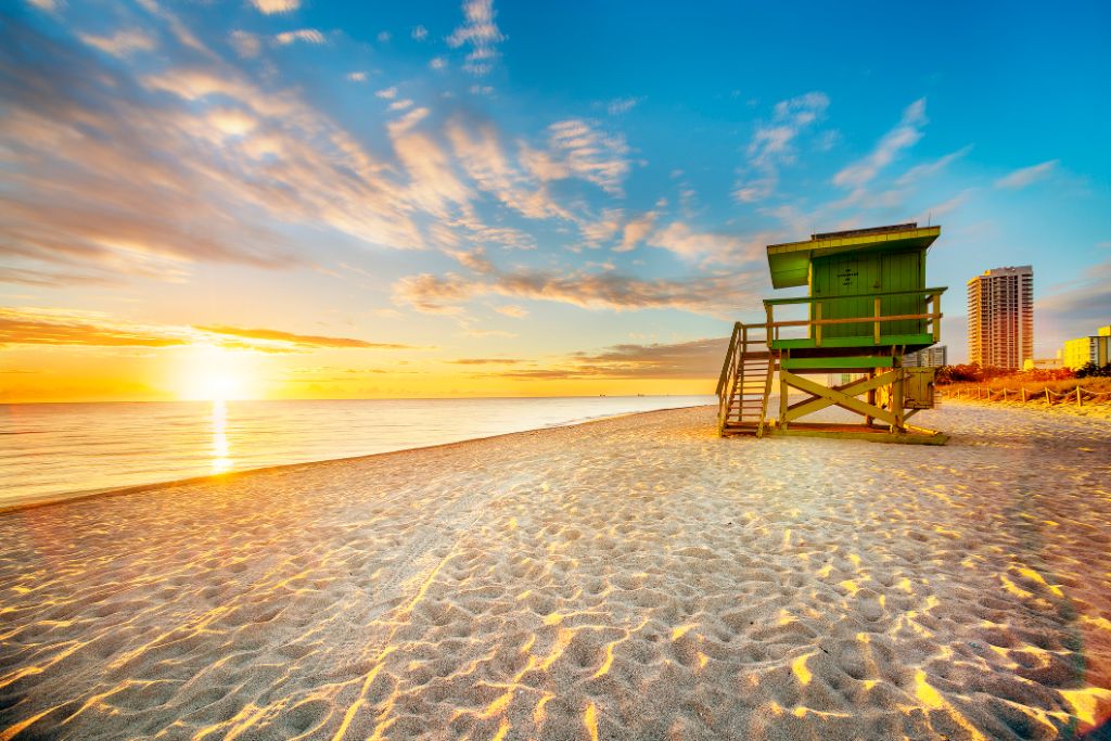 Miami South Beach Sonnenaufgang mit Rettungsschwimmer Turm und Küste mit bunten Wolken und blauem Himmel.