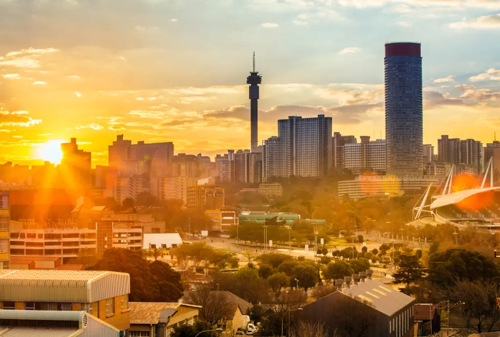 Stadtbild von Johannesburg bei Sonnenuntergang. Zu sehen ist das Hillbrow-Wohnzentrum mit den markanten Ponte-Wohnungen und dem Fernmeldeturm.